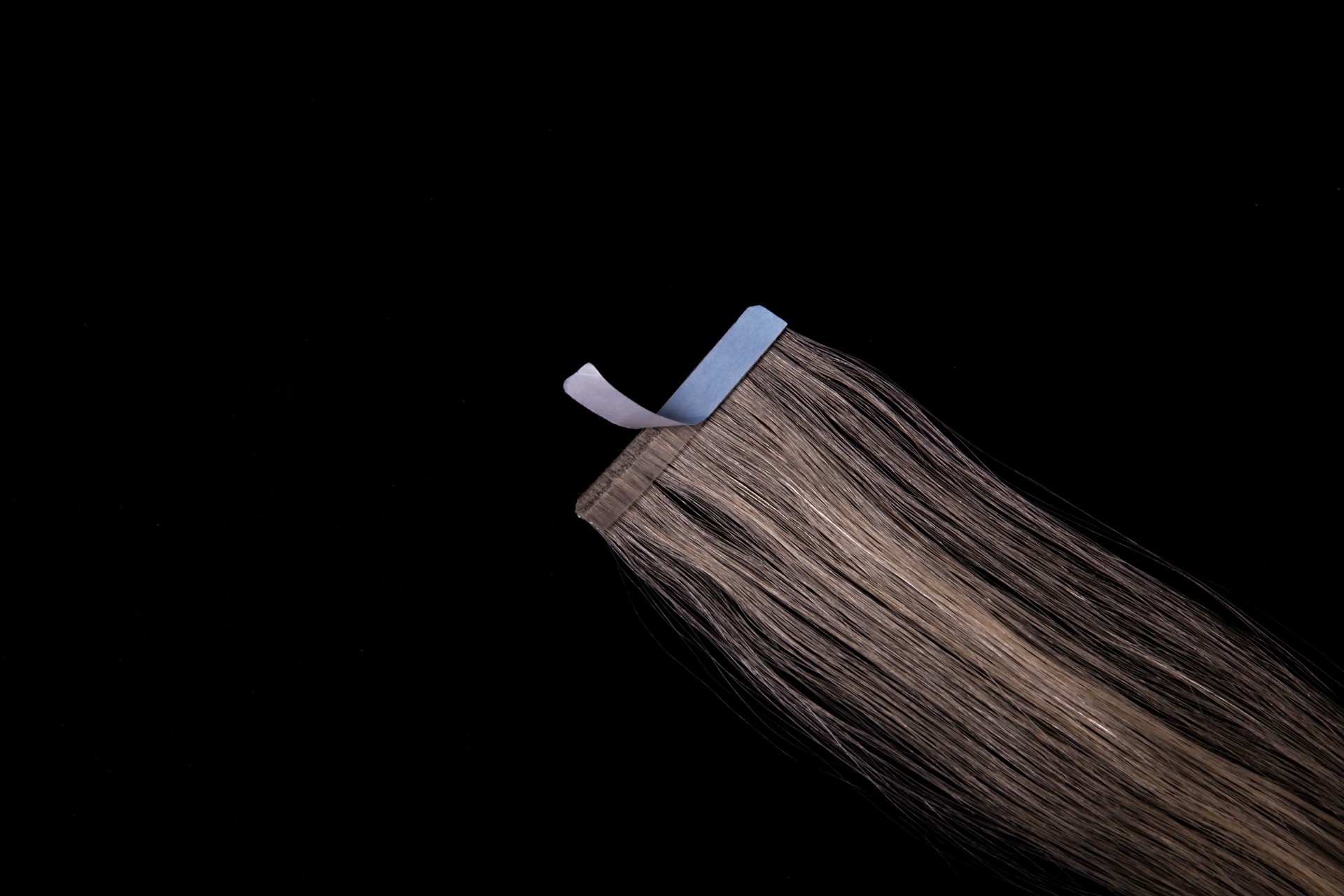 Fake blonde hair on sticky tape on black isolated background